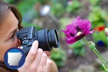 a female photographer photographing a flower close-up - with Arkansas icon