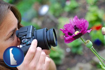 a female photographer photographing a flower close-up - with Delaware icon