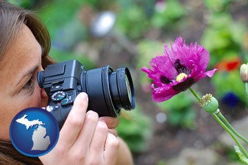 a female photographer photographing a flower close-up - with Michigan icon