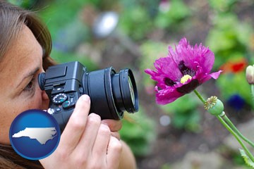 a female photographer photographing a flower close-up - with North Carolina icon