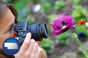 a female photographer photographing a flower close-up - with Nebraska icon