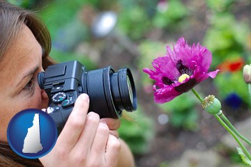 a female photographer photographing a flower close-up - with New Hampshire icon