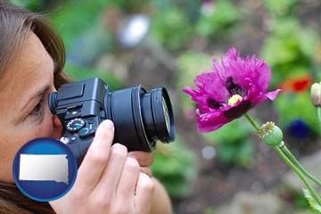 a female photographer photographing a flower close-up - with South Dakota icon