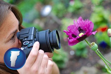 a female photographer photographing a flower close-up - with Vermont icon