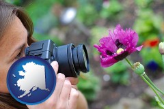 alaska map icon and a female photographer photographing a flower close-up