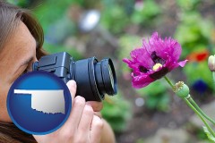 oklahoma map icon and a female photographer photographing a flower close-up